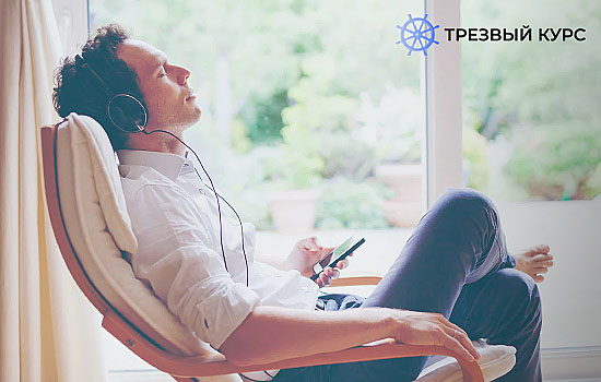 Мужчина на кресле медитирует под музыку в наушниках